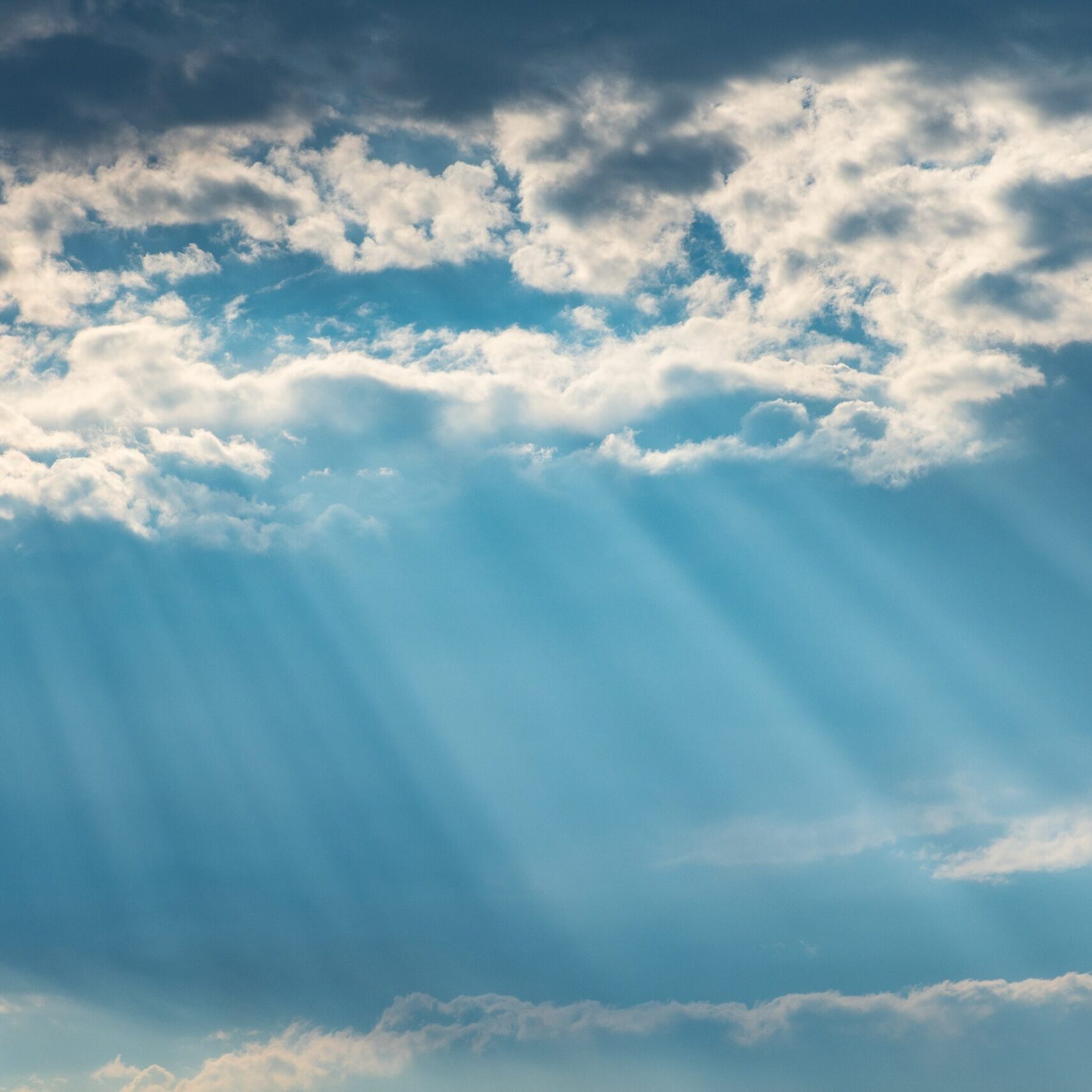 Sun rays burst through clouds against an azure sky. Photo by Brett Sayles from Pexels